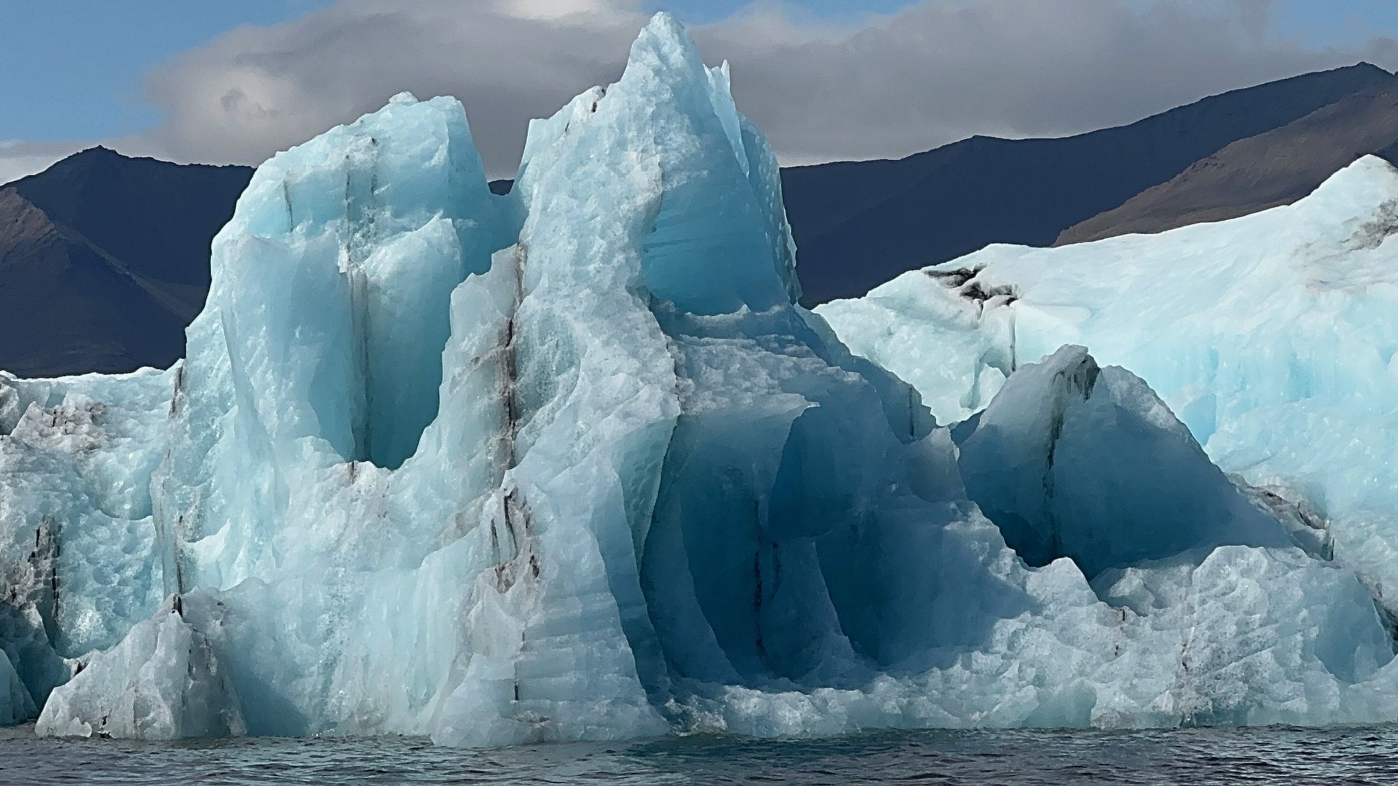A brilliant blue iceberg in Jökulsárlón Glacier Lagoon, dark mountains behind